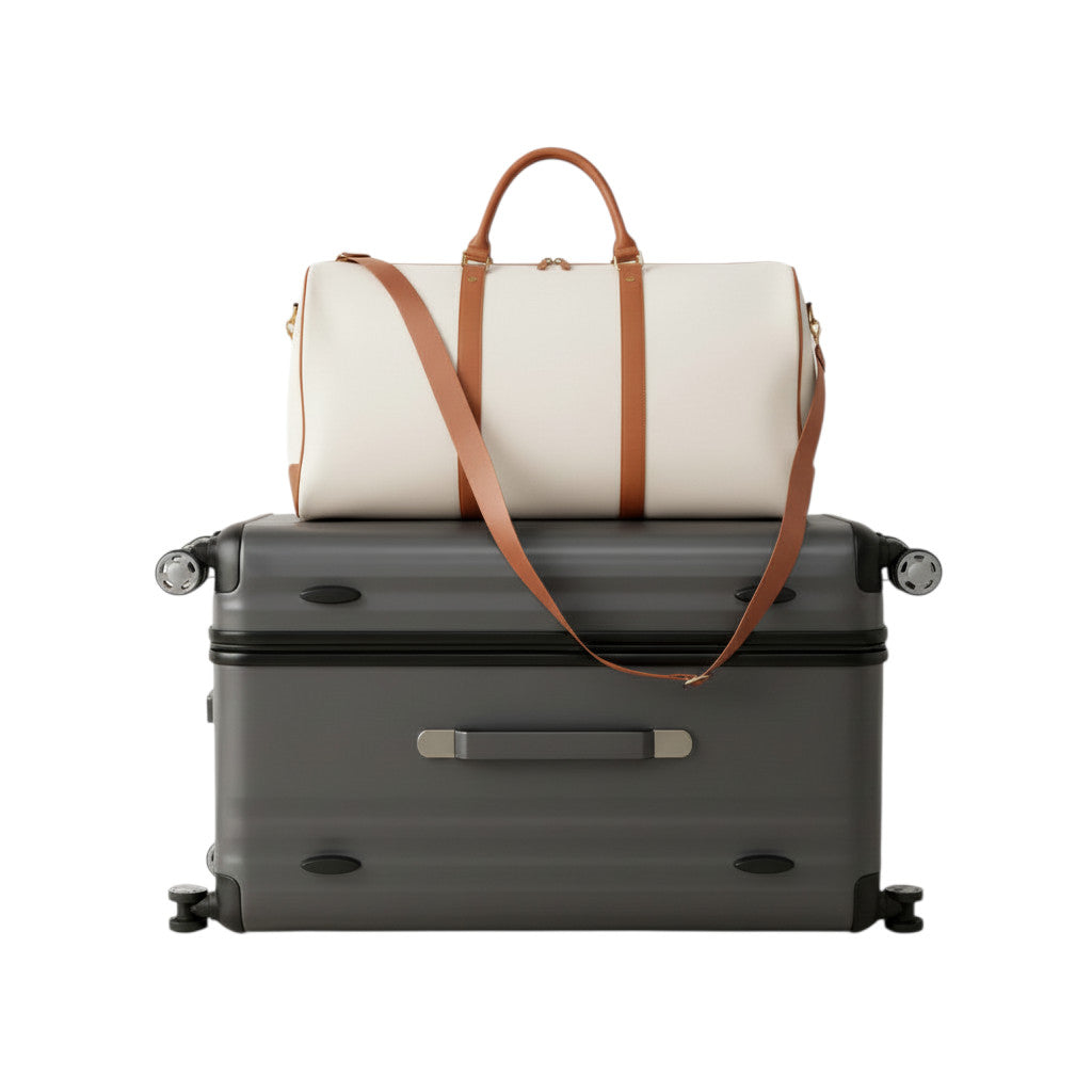 Sac de voyage MoveLite Blossom blanc cassé avec anses et bandoulière en cuir marron posé sur une valise grise