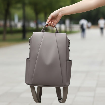 Sac à dos Nomade MoveLite gris élégant en cuir synthétique porté à la main dans un parc