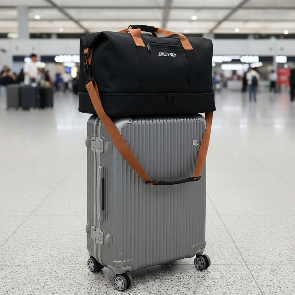 Sac de voyage MoveLite Wanderelle noir avec anses et bandoulière marron posé sur une valise rigide grise à l'aéroport