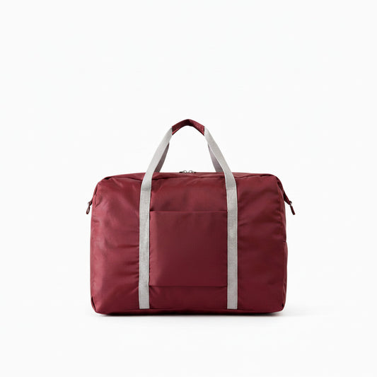 Sac de voyage MoveLite rouge bordeaux avec poignées grises, design minimaliste et compartiment frontal pratique